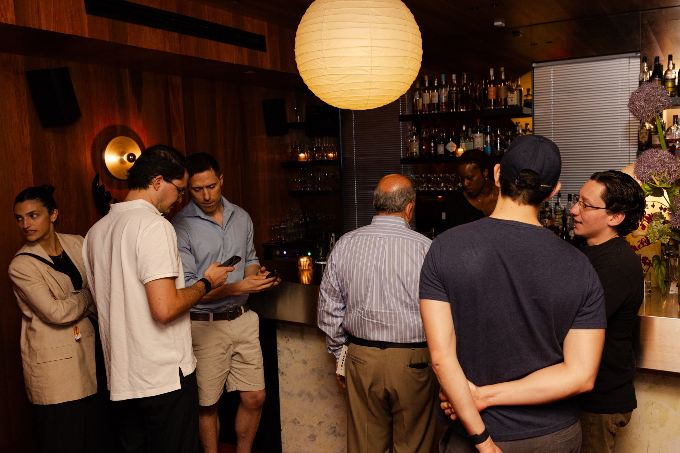 Guests talking beside the wood-panelled bar at Backers & Builders in New York