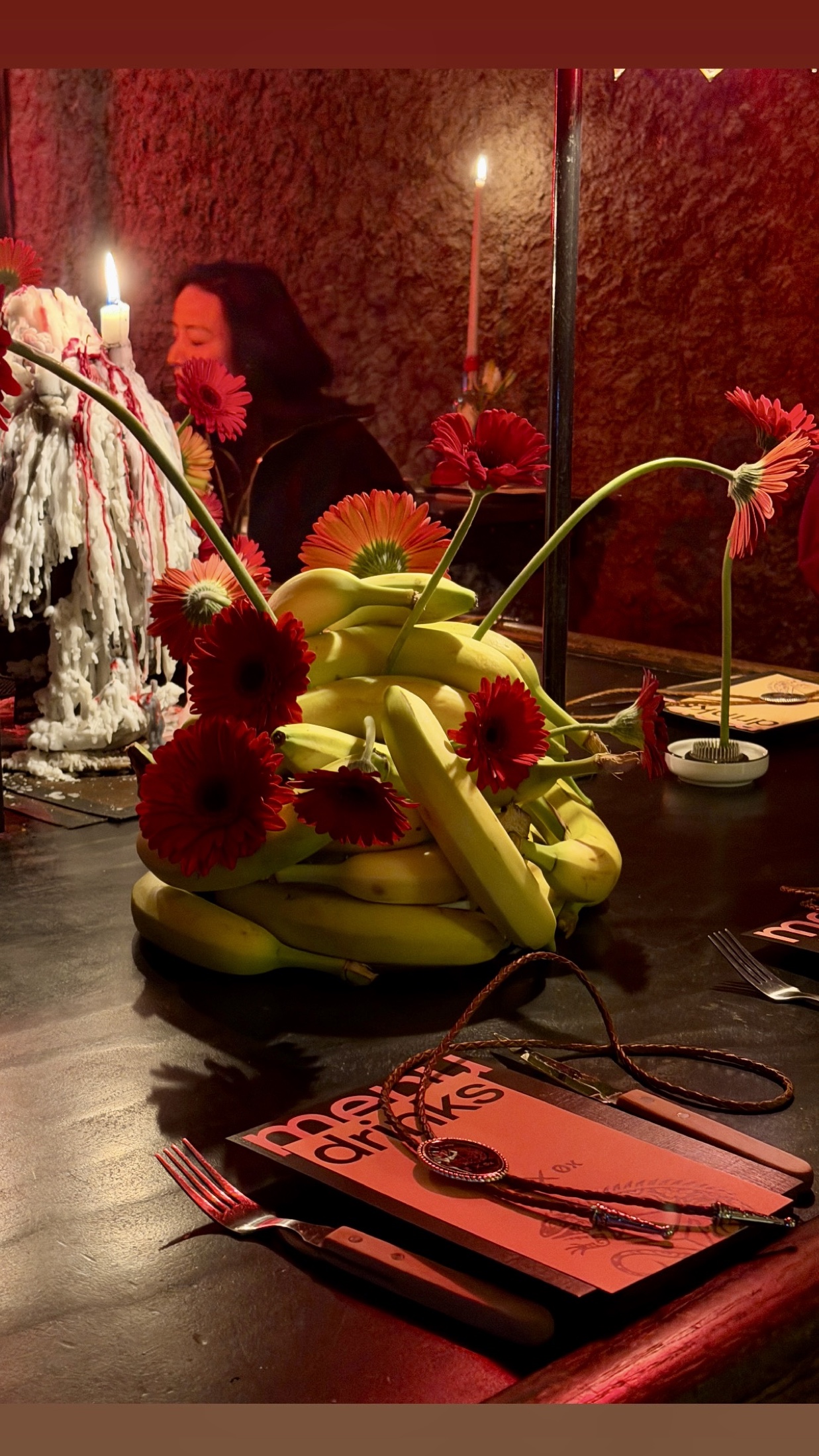 Banana and red floral centerpiece set against candlelight