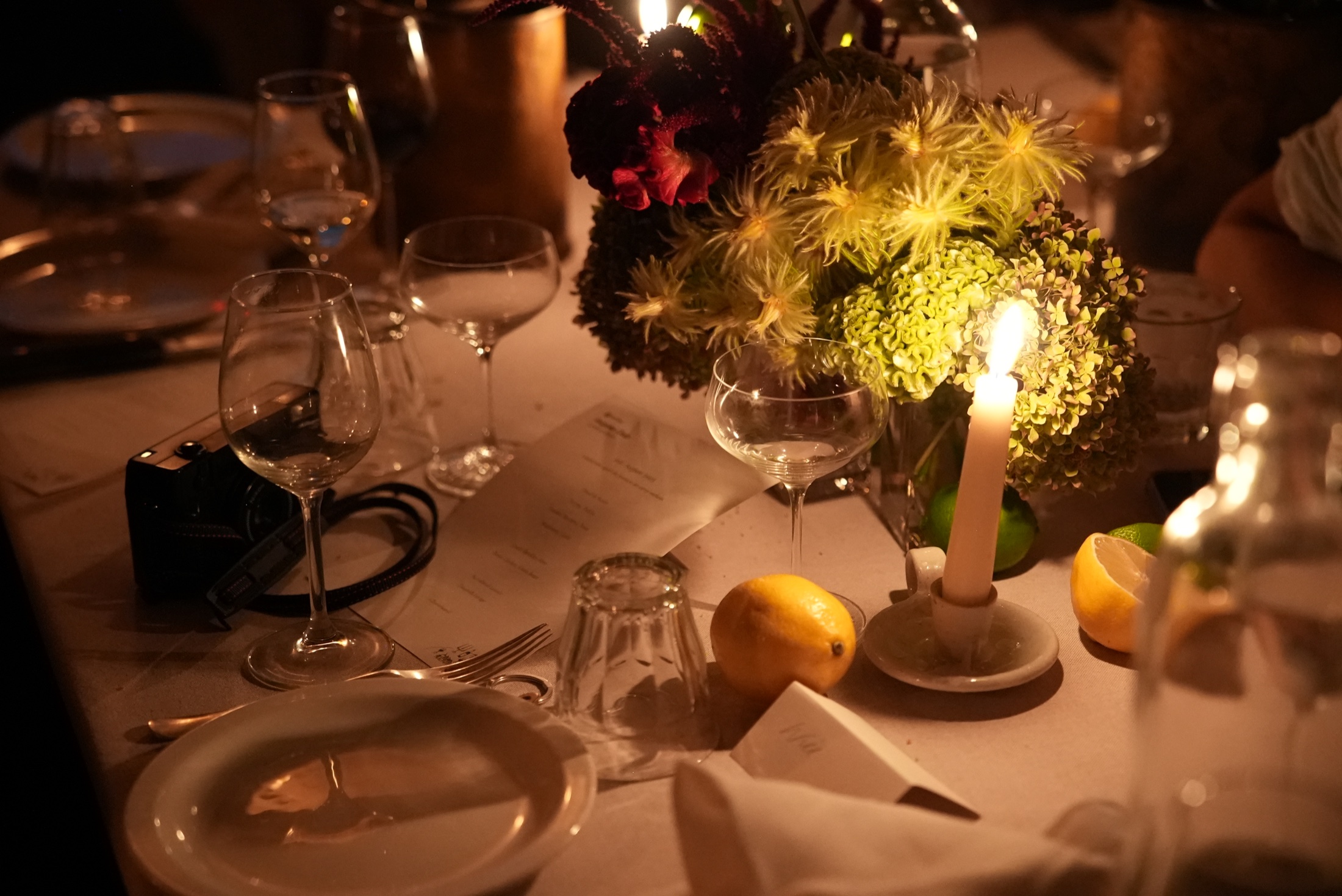 Candlelit London dinner table with sculptural flowers and glassware