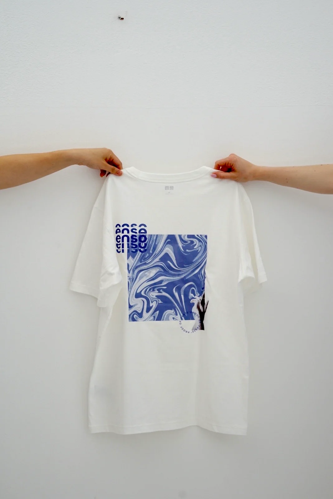 The back of a white Enso T-shirt with a blue marbled graphic