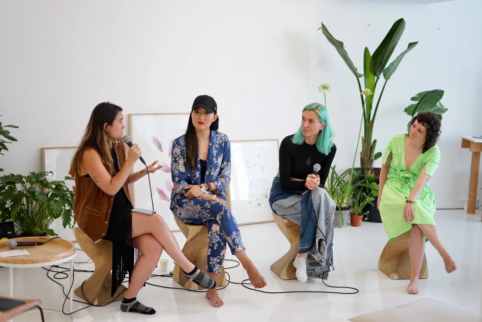 Four panelists in conversation, with microphones and artwork behind them