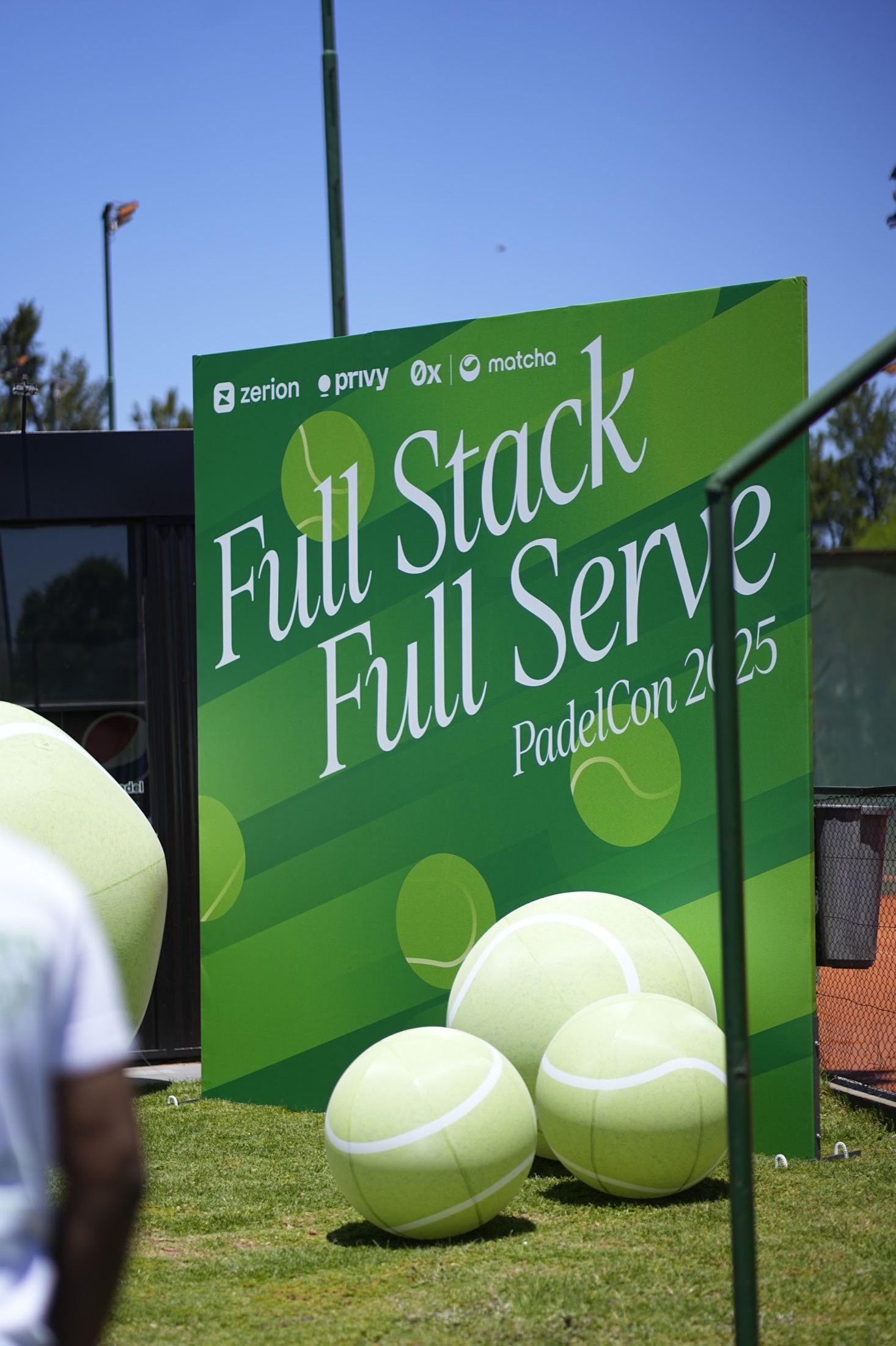 Green PadelCon 2025 event signage with partner logos and oversized tennis ball decorations