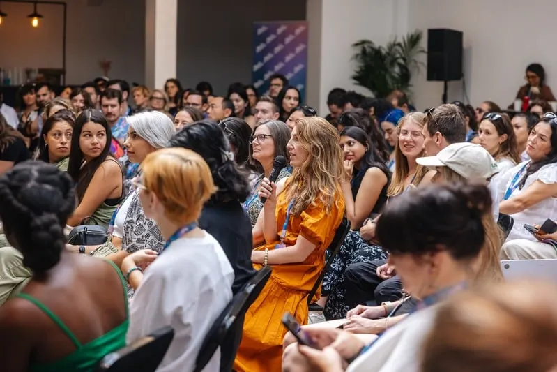 An attendee holding a microphone among the SheFi Summit audience