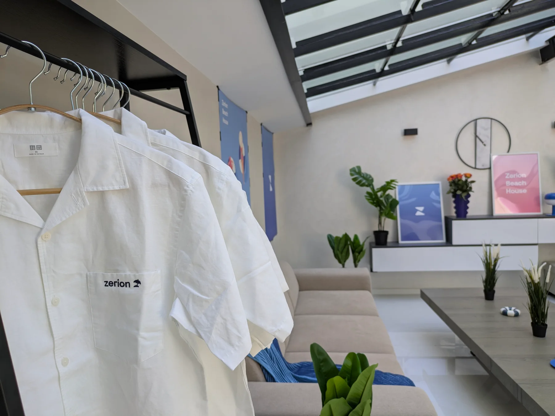 White Zerion-branded shirts on a rail beside the Beach House lounge and signage
